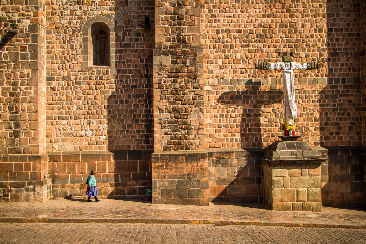 Peruvian woman walking by the church with big cross